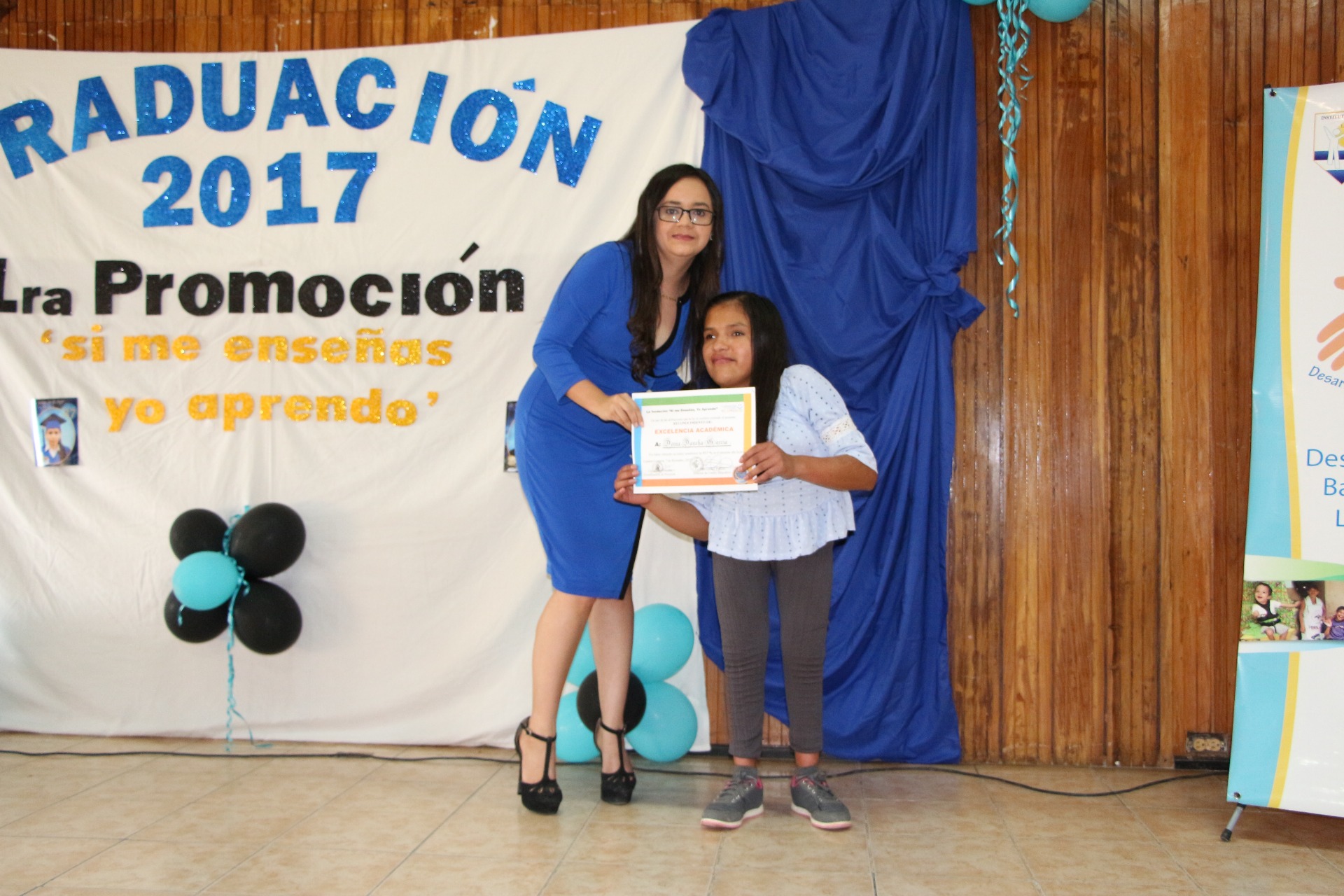 Denia reibiendo reconocimiento de Alumna Destacada del Año por su maestra de grado Gabriela Perez